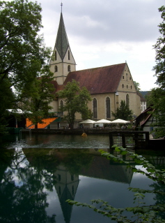 Foto der Klosterkirche Blaubeuren mit einem Spiegelbild im Blautopf